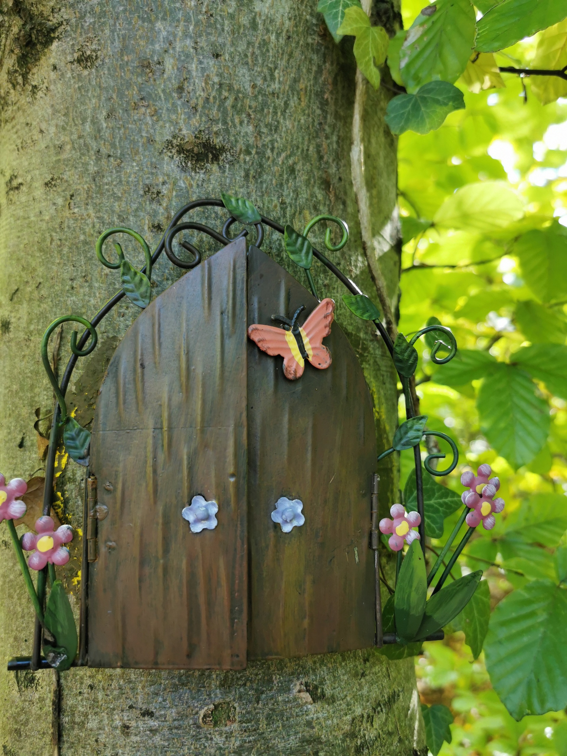 Kleine Wichteltür an einem Baumstamm mitten im Wald