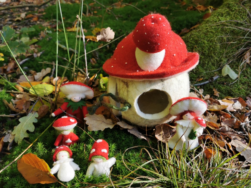 Kleines Fliegenpilzhäuschen aus Filz auf moosigem Waldboden