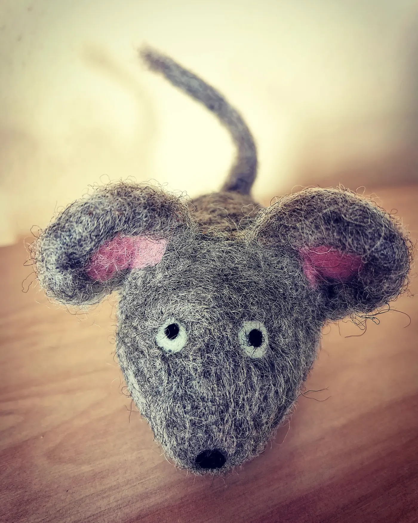 Handgefertigte graue Maus aus Naturfasern auf einem Holztisch