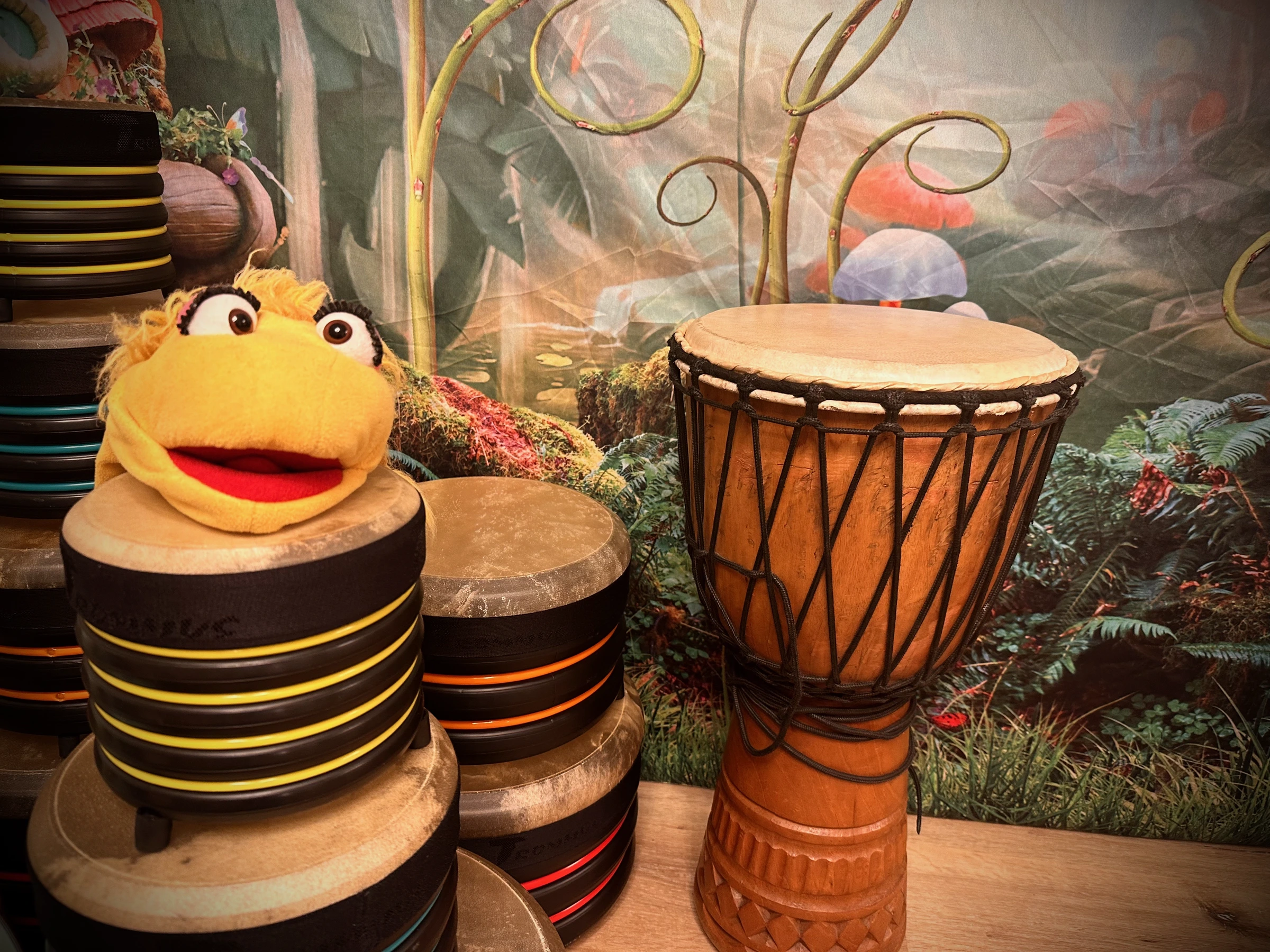 Handpuppe Susi zwischen Trommeln und einer Djembe vor fantasievoller Waldkulisse